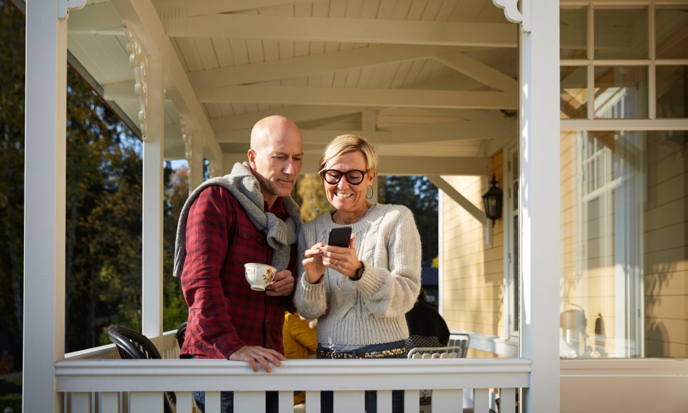 Et par som står på en veranda og ser på en mobil.