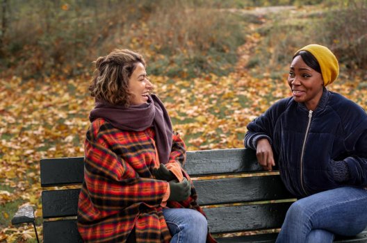 To kvinner på en benk i høstvær.