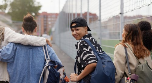 En vennegjeng som går forbi en fotballbane, hvor han ene ser seg tilbake mot kamera og resten ser rett frem