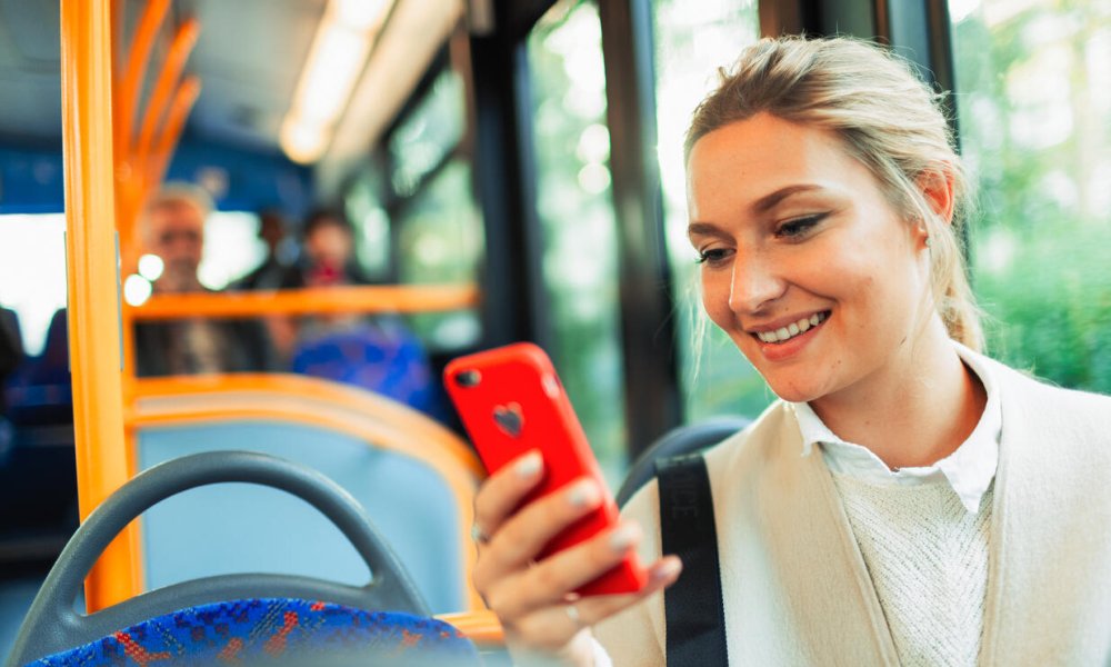 Illustrasjonsfoto. Dame scroller på mobilen mens hun sitter på bussen. 