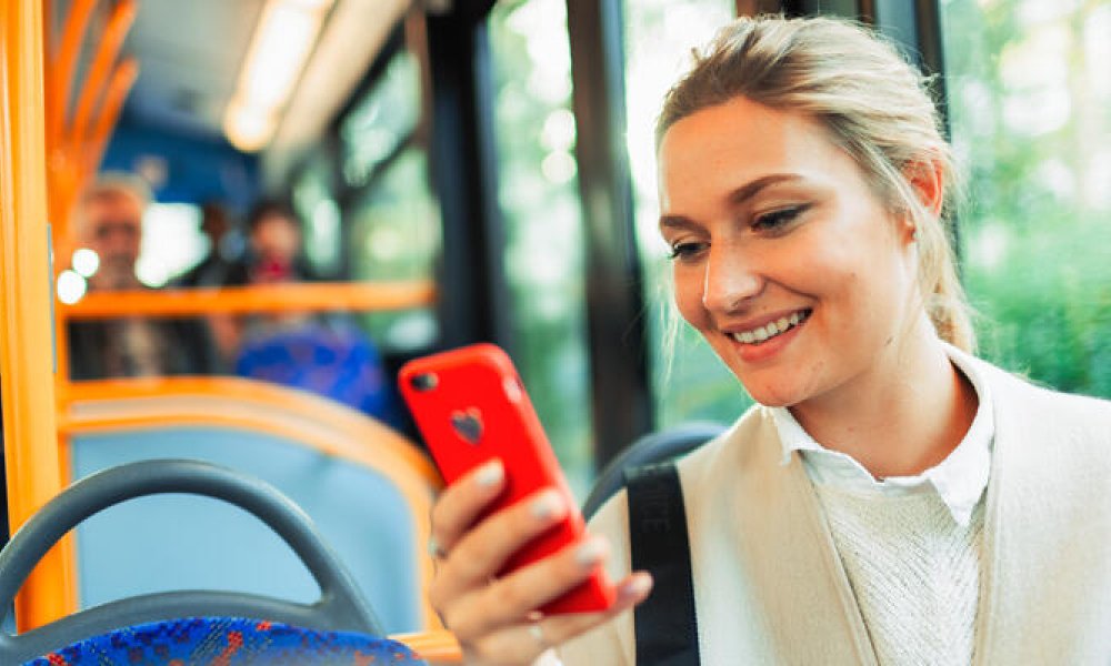 Dame med mobil på bussen.