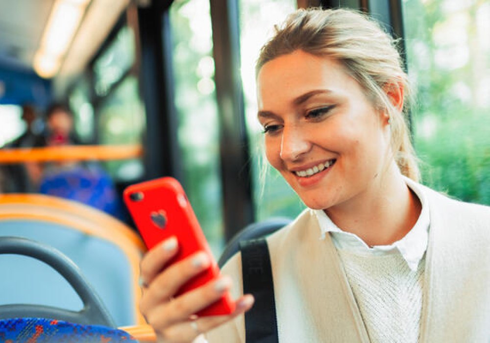 Dame med mobil på bussen.