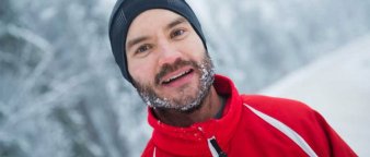 Portrett av mann med lue og snø i skjegget og rød skijakke