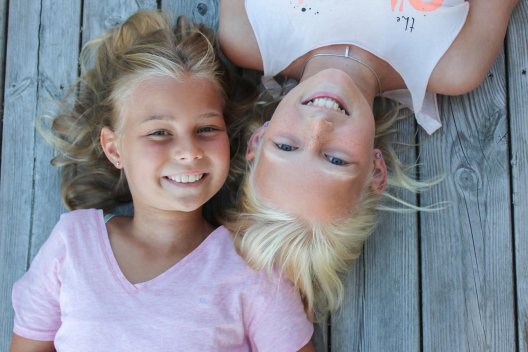 To jenter ligger på brygga og titter opp To jenter ligger på brygga og titter opp