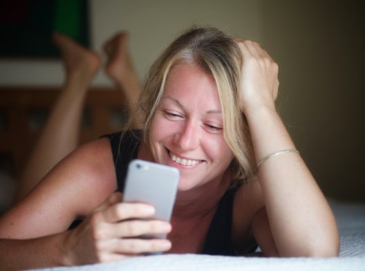 Kvinne ser smilende på mobilen sin. Kvinne ser smilende på mobilen sin.