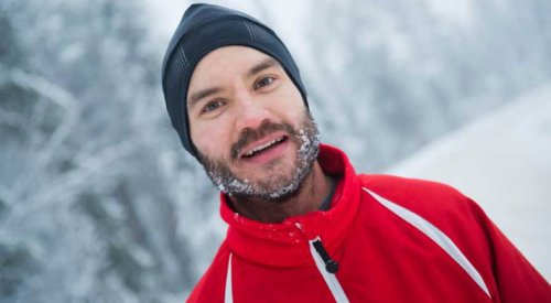 Portrett av mann med lue og snø i skjegget og rød skijakke