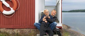 Mor og sønn sitter utenfor en hytte ved sjøen. Mor og sønn sitter utenfor en hytte ved sjøen.