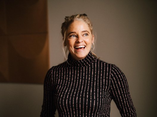 Illustrasjonsfoto, smilende dame med en brun genser. Illustrasjonsfoto, smilende dame med en brun genser.