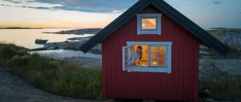 Dame som sitter i vinduet i en rød hytte ved sjøen. Dame som sitter i vinduet i en rød hytte ved sjøen.