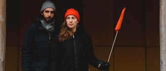 Ungt par med luer som holder rødt flagg. Ungt par med luer som holder rødt flagg.