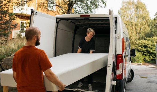 Illustrasjonsfoto: Et par som flytter en seng i flyttebil