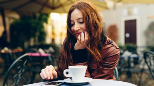 Dame på kafé som drikker kaffe og sjekker mobilen. Dame på kafé som drikker kaffe og sjekker mobilen.