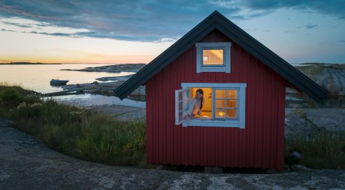 Illustrasjonsfoto: ung kvinne lukker hyttevinduet Illustrasjonsfoto: ung kvinne lukker hyttevinduet