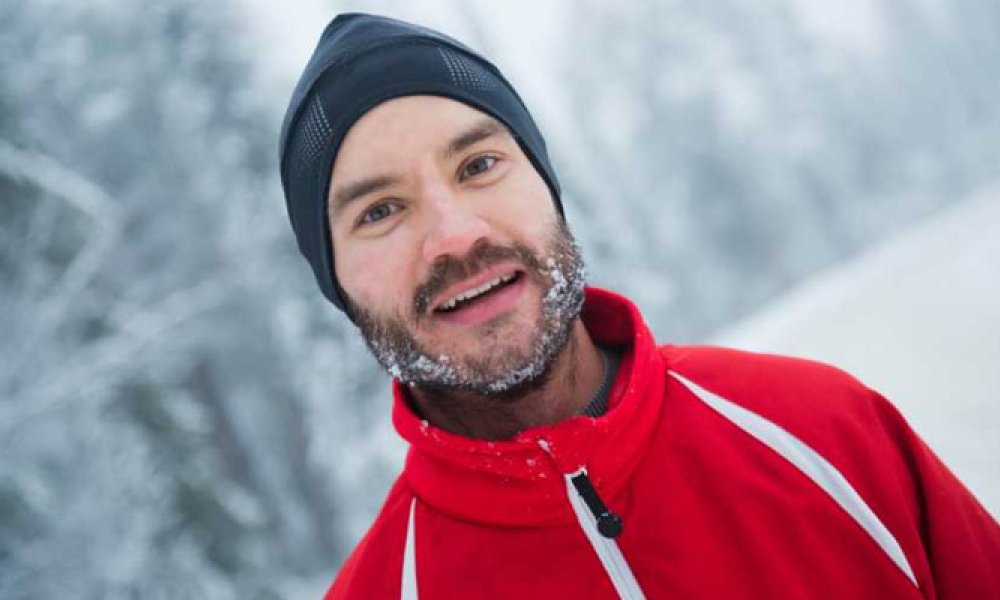 Portrett av mann med lue og snø i skjegget og rød skijakke