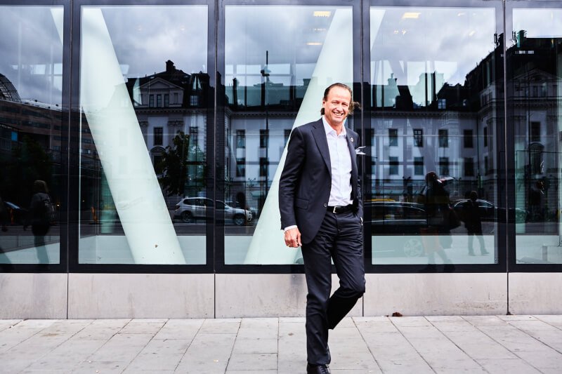 Jan Erik Saugestad foran hovedkontoret på Lysaker. Glassvegger, mørk dress.