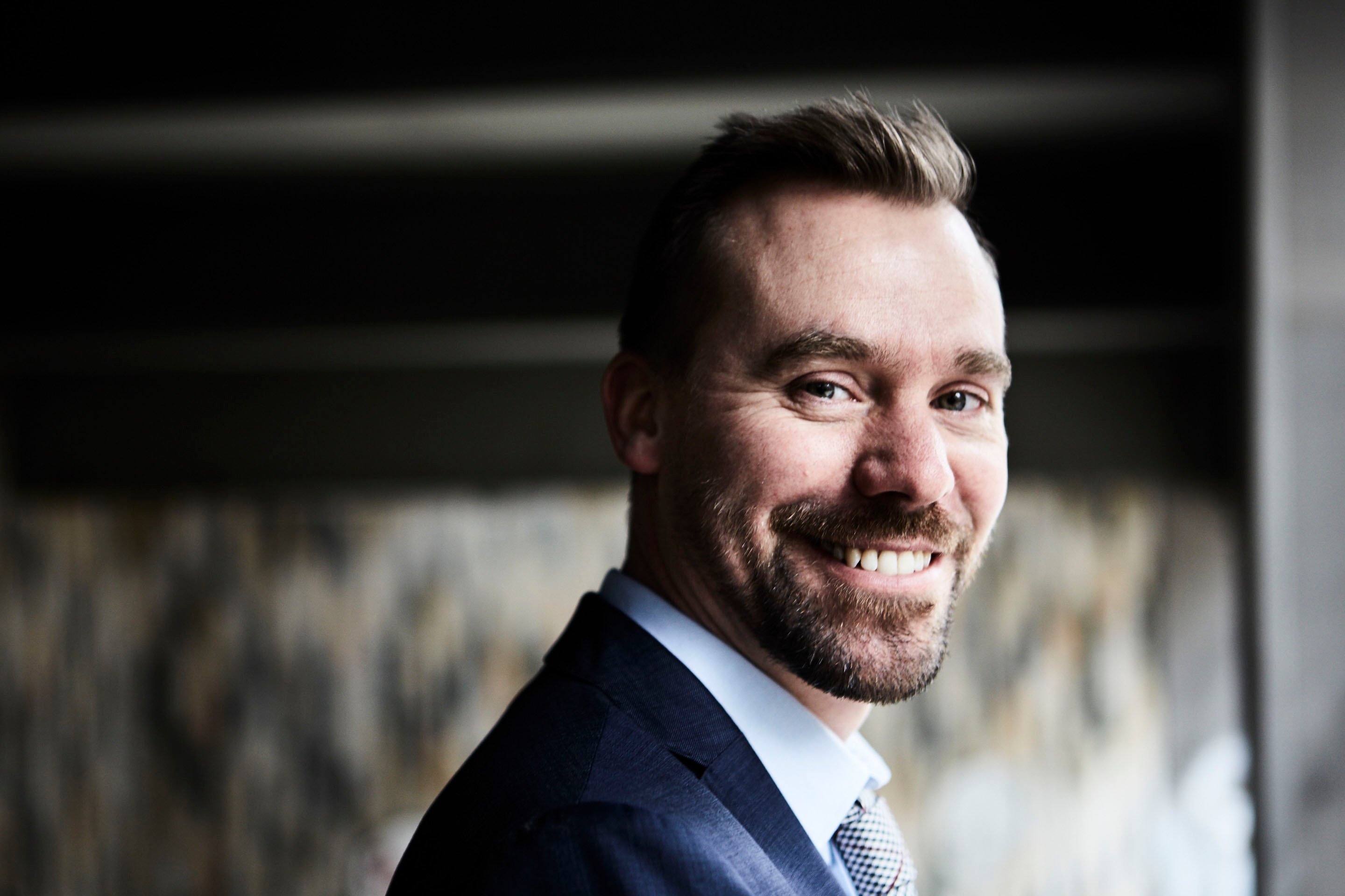 Matthew Smith, portrettfoto. Blå dress, stort smil.